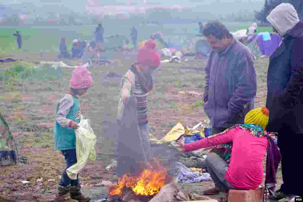 Refugees at Idomeni camp keep warm by burning a soiled blanket. (Jamie Dettmer for VOA)