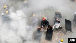 Protesters react as they are engulfed by tear gas fired by police, as other demonstrators set off fire extinguishers, during a demonstration against the military coup in Yangon, Myanmar, on March 6, 2021. 