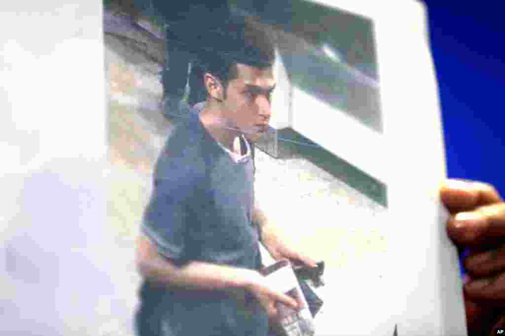 A Malaysian police woman holds up a picture of Pouri Nourmohammadi, 19, an Iranian who boarded the now missing Malaysia Airlines jet MH370 with a stolen passport.