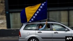 A man waves the Bosnian flag in Sarajevo, Oct. 6, 2018, on the eve of Bosnian tripartite presidency election. Bosnians head to the polls Sunday to elect leaders who will steer the poor nation shackled by the communal divides that fueled its brutal war more than two decades ago.