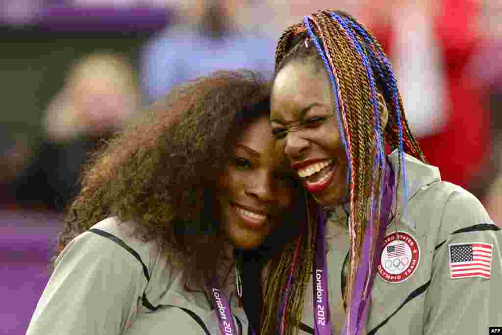 US Serena Williams (L) and Venus Williams celebrate on the podium after receiving their gold medal for winning the London 2012 Olympic Games women's doubles tennis tournament, August 5, 2012.