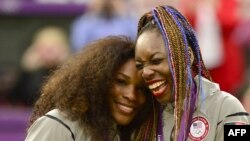 Petenis Serena Williams (kiri) dan kakaknya Venus Williams setelah meraih medali emas nomor ganda putri dalam Olimpiade 2012.