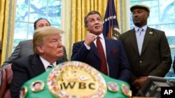 President Donald Trump (L), and heavyweight champion boxer, Lennox Lewis (R) watch with Sylvester Stallone in the Oval Office of the White House in Washington, May 24, 2018, where Trump granted a posthumous pardon to Jack Johnson, boxing's first black heavyweight champion.