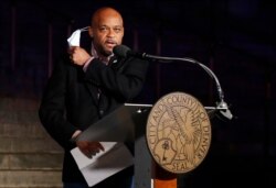 Denver Mayor Michael Hancock pulls off his mask to speak before red and white lights were illuminated on the City/County Building to show support and gratitude for first responders and medical personnel during the outbreak, April 9, 2020, in Denver.