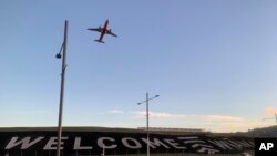 FILE - A sign painted near the runway of the Wellington International Airport greets travelers returning home in Wellington, New Zealand, April 19, 2021. The sign reads "Welcome Whanau" with the second word an Indigenous Maori word meaning family.