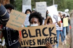FILE - A demonstrator holds a placard during a Black Lives Matter protest, following the death of George Floyd in Minneapolis police custody, in front of the U.S. Embassy in Nairobi, Kenya, June 9, 2020.