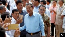 Cambodian Prime Minister Hun Sen, center, of ruling Cambodian People's Party pose for a selfie with his party supporters after a voting in the Senate election Sunday, Feb. 25, 2018. (AP Photo/Heng Sinith)
