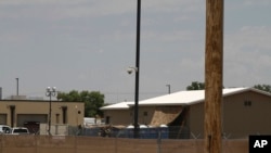 FILE - National Guard soldiers adjust a shade tarp over portable toilets by a building used for the detention of migrant children in Border Patrol custody in Clint, Texas, June 26, 2019. 
