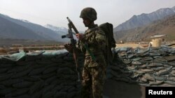 FILE - An Afghan National Army (ANA) soldier keeps watch at the Forward Base in Nari district near the army outpost in Kunar province, in this picture taken Feb. 24, 2014. 