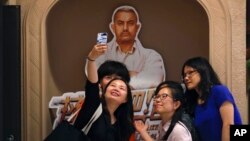 FILE - a group of Chinese women take a selfie with a poster of Indian Bollywood blockbuster film "Dangal" on display at a cinema in Beijing.