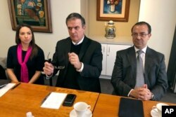 FILE - Mexican Foreign Minister Marcelo Ebrard, center, talks to reporters, Dec. 3, 2018, at the Mexican Embassy in Washington.