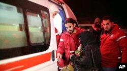 Les membres du Croissant-rouge arabe syrien aident une femme qui porte un bébé à monter au bord d'une ambulance pendant une évacuation de malades de Ghouta oriental, près de Damas, en Syrie, mercredi, le 27 décembre 2017.