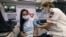 A medic with Israel's Magen David Adom emergency service administers a booster shot of a COVID-19 vaccine to a woman in Tel Aviv, Aug. 14, 2021. 