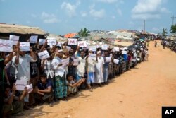 FILE - Rohingya refugees holding placards await the arrival of a U.N. Security Council team at the Kutupalong Rohingya refugee camp in Kutupalong, Bangladesh, April 29, 2018.