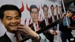 Seorang pengunjuk rasa mengangkat poster yang menggambarkan Kepala Executive Hong Kong Leung Chun-ying (kiri) bertanduk setan pada aksi damai hari pertama di Hong Kong, 1 Januari 2017. (AP Photo/Vincent Yu)