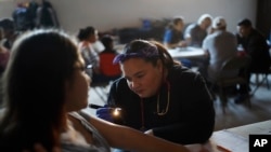 FILE - Dr. Psyche Calderon works with a patient in a shelter for migrants in Tijuana, Mexico, Dec. 14, 2019.