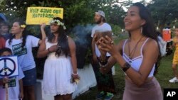 Eva Aguon Cruz, 30, holds a cup with burned flower as a ritual to call for protections from the spirits as about a hundred people gather at Chief Kepuha Park in Hagatna, Guam, for a rally for peace, Aug. 14, 2017. The threatened missile attack by North Korea on Guam has prompted calls for peace from the island's indigenous people, who are weary of yet another conflict after enduring centuries of hostilities. 