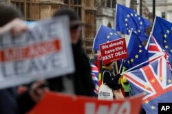 Pro and anti Brexit demonstrators wave their placards and flags outside the Houses of Parliament in London, Dec. 18, 2018.