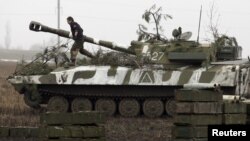 FILE - A member of the self-proclaimed Donetsk People's Republic forces walks atop a self-propelled artillery gun during tactical training exercises in Ukraine's Donetsk region, Feb. 4, 2016. 