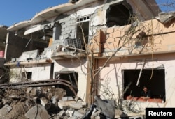 A man looks out of the window of a house destroyed by an Islamic State suicide car bomb attack in Mosul, Iraq, Nov. 20, 2016.