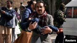 Seorang pria menggendong seorang anak laki-laki dari Gereja Methodis Bethel Memorial di Quetta, Pakistan, setelah serangan bom, 17 Desember 2017.