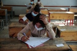 FILE - Students wear face masks to help curb the spread of the coronavirus as they take a final-term school exam at a public school in Sanaa, Yemen, Aug. 15, 2020.