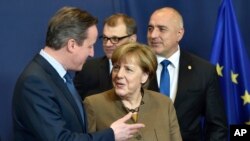 PM Inggris David Cameron (kiri) berbicara dengan Kanselir Jerman Angela Merkel di sela KTT Uni Eropa di Brussels, Belgia, Rabu (18/2).