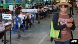 A Thai voter passes election staff at a polling station in Samut Songkhram province, south of Bangkok on March 2, 2014. Polls opened peacefully in five Thai provinces for re-runs of a widely disrupted general election.