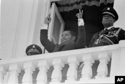 FILE - Jean-Claude Duvalier, son of Haitian dictator Francois "Papa Doc" Duvalier, is flanked by military guards as he reviews the troops at the Presidential Palace in Port-au-Prince, Haiti, April 14, 1971. When Jean-Claude Duvalier was ousted and fled to France in 1986, a repressive army high command of Duvalier appointees remained largely intact.