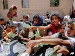 FILE: In this April, 13, 2017 file photo, Yemenis present documents in order to receive food rations provided by a local charity, in Sanaa, Yemen.