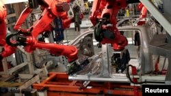 FILE - Robots work on the cab of a 2019 Ram pickup at the Fiat Chrysler Automobiles Sterling Heights Assembly Plant in Sterling Heights, Mich., Oct. 22, 2018. Manufacturing is one are where robots are part of the workforce.