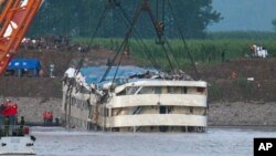 Rescuers watch the capsized ship Eastern Star being lifted by cranes on the Yangtze River in Jianli county of southern China’s Hubei province, as seen from across the river from Huarong county of southern China’s Hunan province, June 5, 2015. 