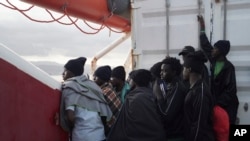 FILE - Men wait to disembark from the Ocean Viking ship as it reaches the port of Messina, Italy, Sept. 24, 2019.
