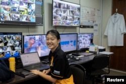 An employee smiles while watching surveillance monitors at Apollo Aquaculture Group's three-tiered vertical fish farm in northern Singapore, May 4, 2019. REUTERS/Loriene Perera