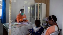 Seorang tenaga kesehatan berbicara dengan seorang perempuan dibalik pelindung plastik untuk mencegah penularan virus corona di sebuah puskesmas di Yalimo, Provinsi Papua, 21 April 2020. (Foto: AP)