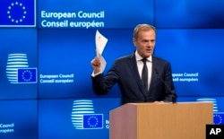 European Council President Donald Tusk holds up the Article 50 document from the UK during a media conference at the Europa building in Brussels, March 29, 2017.