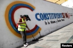 A woman sweeps a sidewalk in front of graffiti which reads "Constituent yes, it goes" in Caracas, Venezuela, July 24, 2017.