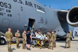 In this image courtesy of the US Air Force, medical support personnel from the 86th Medical Group help an Afghan mother and family off a US Air Force C-17, call sign Reach 828, moments after she delivered a child aboard the aircraft upon landing at Ramste