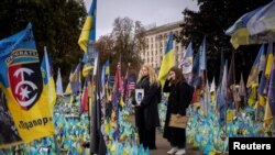 Women hold portraits of loved ones who were killed fighting amid Russia's invasion of Ukraine, at a memorial site for fallen Ukrainian soldiers as the country marks Defenders of Ukraine Day, in Kyiv, Oct. 1, 2024. 