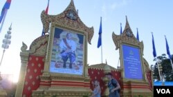 រូបឯកសារ៖ ភ្ញៀវ​ទេសចរ​ដើរ​កាត់​មុខ​ព្រះឆាយាលក្ខណ៍​ព្រះបរមនាថ​ នរោត្តម​ សីហមុនី​ ព្រះ​មហាក្សត្រ​នៃ​ព្រះរាជាណាចក្រ​កម្ពុជា​ ដែល​ត្រូវ​បាន​ដាក់​តាំង​នៅ​មុខ​វិមាន​ឯករាជ្យ​ក្នុង​ឱកាស​ខួប​ទី​១១​នៃ​ព្រះ​រាជ​ពិធី​បុណ្យ​​គ្រង​រាជ​សម្បតិ្ត​ កាល​ពី​ល្ងាច​ថ្ងៃ​ទី​២៨ ខែ​តុលា​ ឆ្នាំ​២០១៥។ (នូវ ពៅ​លក្ខិណា​/VOA) 