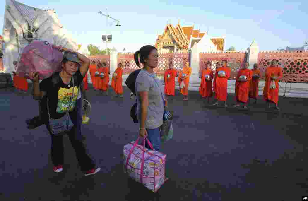 Anti-government demonstrators leave a demonstration site&nbsp;with their belongings, walking past Buddhist monks a day after military soldiers staged a coup, in Bangkok, May 23, 2014.