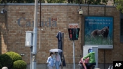Residents pass by the Canadian Embassy in Beijing on June 19, 2020. Chinese prosecutors charged two detained Canadians with spying on Friday.