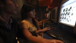 A couple share a computer to browse Facebook at an Internet cafe in Jakarta, Indonesia