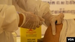 រូបឯកសារ៖ បុគ្គលិកសុខាភិបាលចាក់វ៉ាក់សាំងបង្ការ​ជំងឺកូវីដ១៩ របស់ក្រុមហ៊ុន AstraZeneca ដល់ក្រុមពលរដ្ឋដែលមានអាយុ ៦០ ឆ្នាំឡើងទៅ នៅមជ្ឈមណ្ឌលការចាក់វ៉ាក់សាំង​ក្នុង​មន្ទីរពេទ្យបង្អែករាជធានីភ្នំពេញ កាលពីថ្ងៃទី២៣ ខែមីនា ឆ្នាំ២០២១។ (ទុំ ម្លិះ/វីអូអេ)