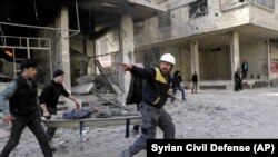 SYRIA -- Members of the Syrian Civil Defense group carry a man who was wounded during airstrikes and shelling by Syrian government forces, in Ghouta, a suburb of Damascus, February 20, 2018