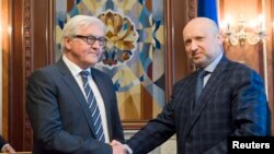 Presiden sementara Ukraina Oleksander Turchinov (kanan) berjabat tangan dengan Menlu Jerman Frank-Walter Steinmeier (kiri) dalam pertemuan di Kyiv (13/5).