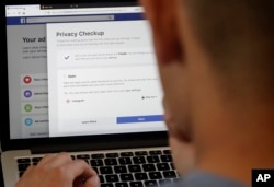 A man poses for photos in front of a computer showing Facebook ad preferences pages in San Francisco, March 26, 2018. Facebook is giving its privacy tools a makeover as it reels from criticisms over its data practices and faces tighter European regulations.