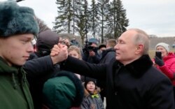 President Vladimir Putin shakes hands with a man after attending a wreath laying commemoration ceremony for the 77th anniversary since the Leningrad siege was lifted during World War II at the Piskaryovskoye Memorial Cemetery, Jan. 14, 2020.