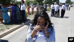 A woman reacts with others as they await word on a shooting at a Sikh temple in Oak Creek, Wis., Sunday, Aug. 5, 2012, where police and witnesses describe a chaotic situation with an unknown number of victims, suspects and possible hostages.