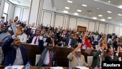 Somali parliament members raise their hands to approve the appointment of new Prime Minister Mohamed Hussein Roble, in Mogadishu, Sept. 23, 2020.